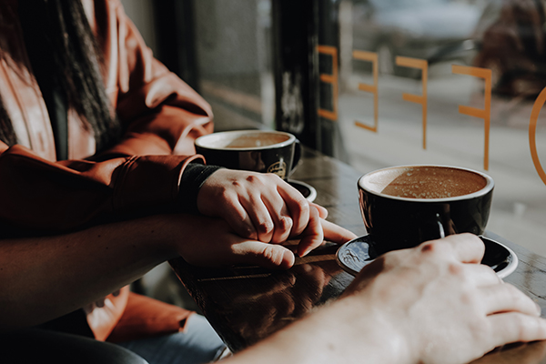 A couple holding hands and drinking coffee